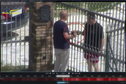 Roma. Un par de personas intercambian dinero tras una reja.