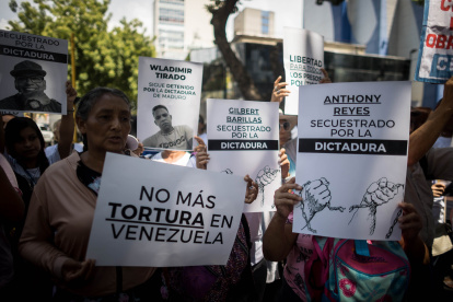 Personas con carteles que muestran imágenes de detenidos durante una manifestación frente a la sede del Ministerio de Servicio Penitenciario, en Caracas.