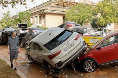 Un hombre camina junto a varios vehículos afectados por las intensas lluvias de la fuerte DANA que afecta especialmente el sur y el este de la península ibérica.