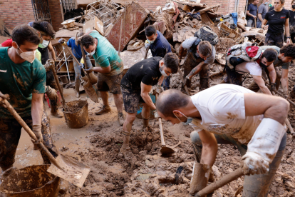 Varias personas retiran el lodo acumulado en una calle de la localidad valenciana de Paiporta, este sábado.