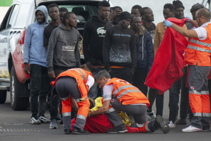 Un inmigrante es atendido a su llegada al puerto de Arrecife en Lanzarote entre un grupo de personas que intentaban llegar a las costas canarias, este domingo 3 de noviembre.
