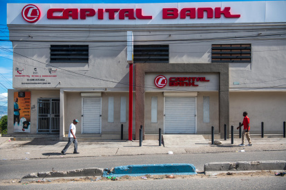Personas caminan frente a locales de comercio cerrados este lunes en Puerto Príncipe (Haití).