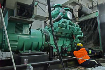 Empresa. Un trabajador da mantenimiento a un generador eléctrico industrial para que funcione las 24 horas.