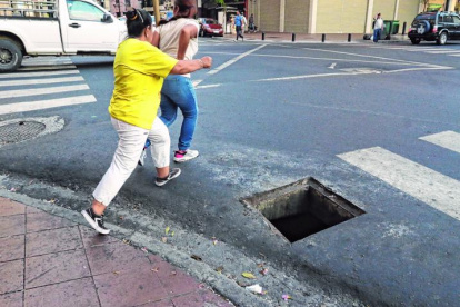 Ciudadanas cerca de caer en la alcantarilla por cruzar la calle.