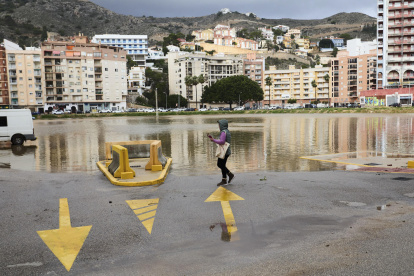 Una mujer camina junto a un aparcamiento público anegado, en Cullera, ciudad que se ha visto afectada por fuertes lluvias esta madrugada aunque sin causar graves incidentes.