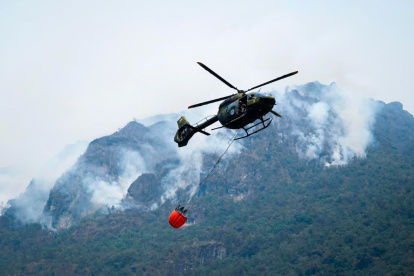 Fotografía cedida por el Cuerpo de Bomberos de Cuenca de un helicóptero combatiendo un incendio forestal en el Parque Nacional Cajas, en Cuenca (Ecuador).
