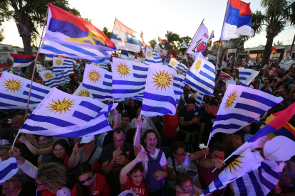 Simpatizantes del candidato por el partido Frente Amplio, Yamandu Orsi, ondean banderas uruguayas y del partido mientras asisten a su mitin de cierre de campaña.