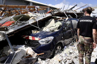 Pamandzi (Mayotte). Un gendarme francés observa el coche de la Gendarmería bajo edificios derrumbados