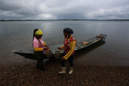 Fotografía del 9 de diciembre de 2024 de dos mujeres recolectoras de piangua bajando de una canoa, en la vereda La Plata de Bahía Málaga (Colombia). EFE/ Ernesto Guzmán Jr.