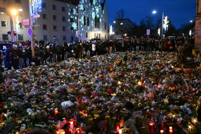Los dolientes se ubican alrededor de monumento improvisado con flores y velas para las víctimas de un ataque con coche en un mercado navideño en Magdeburgo.