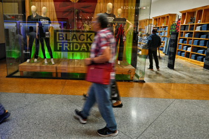 La gente camina frente a una tienda durante una venta del Viernes Negro en Caracas el 29 de noviembre de 2024.