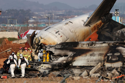 Los bomberos trabajan en los restos del avión Jeju Air siniestrado este domingo 29 de diciembre en el aeropuerto surcoreano de Muan.