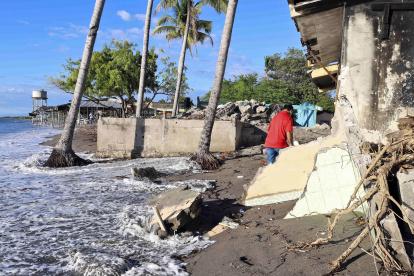 Un hombre camina por viviendas destruidas en la costa de la comunidad de Cedeño (Honduras).
