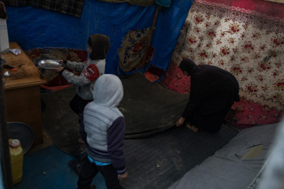 Una mujer palestina desplazada internamente limpia su tienda con sus hijos.