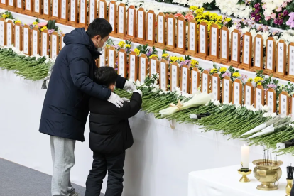 Un niño y su padre colocan una flor en un gimnasio de Muan, condado de Muan, Corea del Sur.