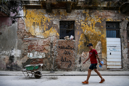 Un hombre pasa junto a un grafiti que dice "Tienes que ser feliz" del artista cubano Mr. Sad en La Habana.