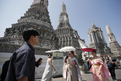 Turistas extranjeros vestidos con trajes tradicionales tailandeses visitan el Templo del Amanecer, o Wat Arun, en Bangkok, Tailandia, el 6 de enero de 2025.
