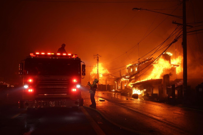 Los bomberos trabajan mientras el incendio forestal de "Palisades" quema varias estructuras a lo largo de la Pacific Coast Highway en Malibú, California.