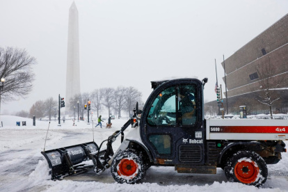 Una máquina quitanieves limpia una acera cerca del Monumento a Washington en la Explanada Nacional en Washington, DC, EE. UU.