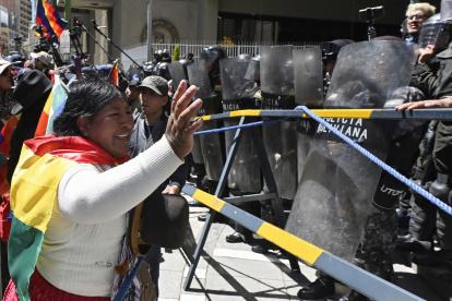Una partidaria del expresidente Evo Morales, hace un gesto frente a agentes de la policía antidisturbios durante la marcha "Comunales por la Vida" contra el gobierno de Luis Arce