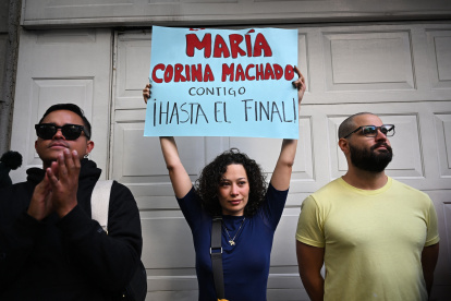 Una mujer sostiene un cartel que dice "María Corina Machado, contigo hasta el final" durante una protesta convocada por la oposición en vísperas de la toma de posesión presidencial en la Ciudad de México