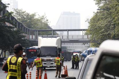 Los funcionarios de tránsito monitorean los vehículos en los puntos de control para detectar emisiones de humo como parte de una campaña de reducción de la contaminación en Bangkok