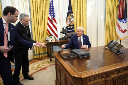 El presidente de Estados Unidos, Donald Trump (derecha), firma órdenes ejecutivas en la Oficina Oval de la Casa Blanca en Washington, DC.