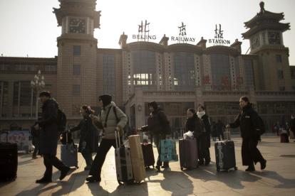 Varios turistas caminan caminoa a la estación de trenes de Pekín.