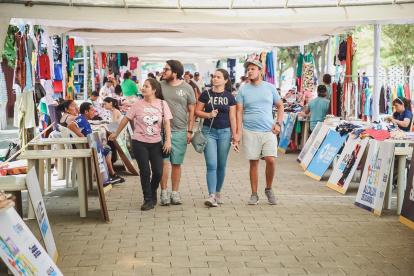 Visitantes recorren la feria de comerciantes en el parque samanes.