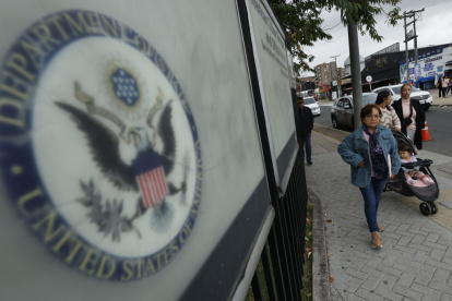 Ciudadanos colombianos solicitantes de visa de los Estados Unidos caminan afuera de la embajada estadounidense este lunes, en Bogotá (Colombia).