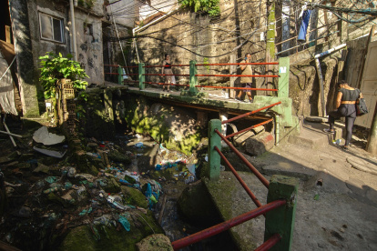La gente camina en un callejón con aguas residuales a cielo abierto en la favela Rocinha, Río de Janeiro, Brasil, el 18 de noviembre de 2024.