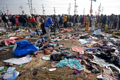 Devotos caminan cerca de telas mezcladas en el suelo tras un accidente por estampida durante el festival Kumbh Mela cerca de Sangam Ghat Prayagraj, Uttar Pradesh (India).