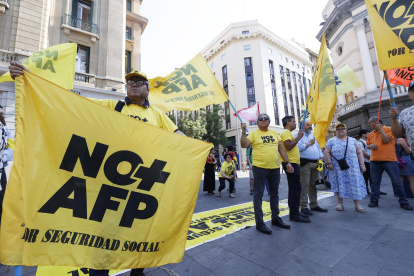 Personas sosteniendo banderas durante una manifestación en contra de las Administradoras de Fondos de Pensiones (AFP), en Santiago (Chile).