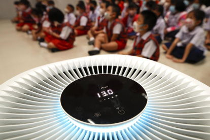 Bangkok. Niños de jardín de infantes se sientan dentro de una habitación equipada con un purificador de aire.