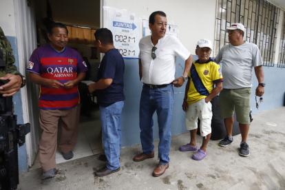 Hombres esperan para votar este domingo, en un puesto de votación en Olón (Ecuador).