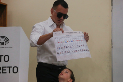 El presidente de Ecuador, Daniel Noboa, muestra su voto acompañado de su hijo Álvaro este domingo, en un puesto de votación en Olón (Ecuador).