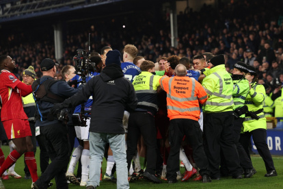 La policía tiene que intervenir para separar a jugadores de ambos equipos durante el partido de la Premier League que han jugado Everton FC y Liverpool FC.