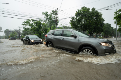 Fotografía de archivo en la que se registró el paso de varios vehículos por una calle inundada en la provincia ecuatoriana de Guayas.