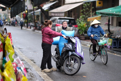 La gente carga bolsas de arroz en una motocicleta en una calle de Hanoi, Vietnam, el 18 de febrero de 2025.