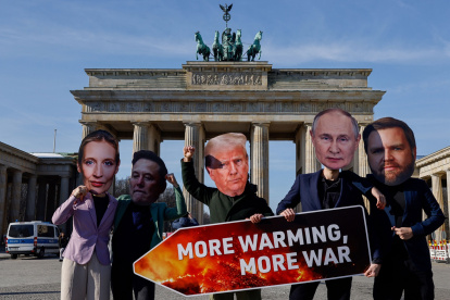 Activistas con máscaras de líderes del mundo sostienen un cartel que dice "Más calentamiento, más guerra".