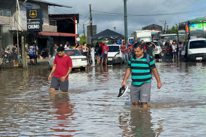 Ciudadanos caminan entre el agua acumulada en una vía en la parroquia Calderón, en Portoviejo, zona rural de Portoviejo.