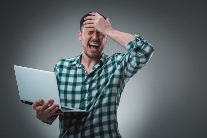 Portrait of young handsome man using laptop, wearing plaid shirt. Studio shot. Emotions