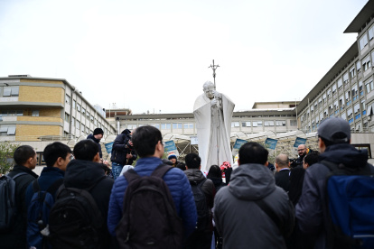 Un grupo de la comunidad vietnamita de Roma reza ante la estatua de Juan Pablo II afuera del hospital Gemelli, donde está hospitalizado el Papa.