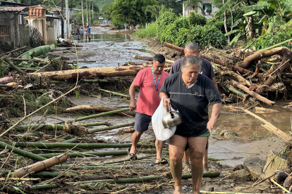 Ana Segovia y otros vecinos caminan entre la palizada de lo que era la vía principal de El Mate, en la parroquia Calderón, Portoviejo en Manabí.
