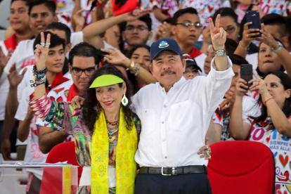 El presidente Daniel Ortega y su esposa, Rosario Murillo, hacen el signo V durante la conmemoración de aniversario de la Revolución Sandinista en la plaza La Fe en Managua.