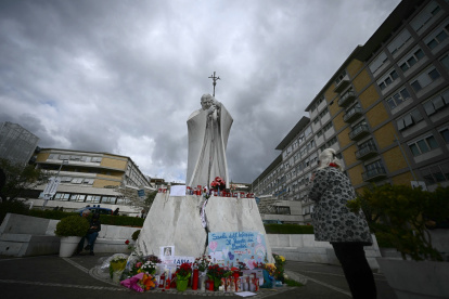 Una mujer reza ante la estatua de Juan Pablo II afuera del hospital Gemelli, donde el Papa Francisco está hospitalizado con neumonía, en Roma, el 28 de febrero de 2025.