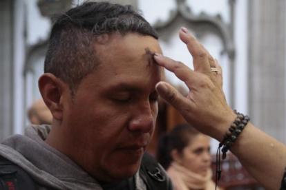 Un creyente católico recibe la cruz de ceniza en su frente en una misa.