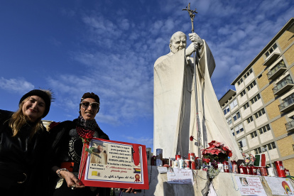 Rome (Italy), 02/03/2025.- Faithful with a sign stand in front of the statue of Pope John Paul II at the entrance to the Gemelli Hospital, where Pope Francis is hospitalized, in Rome, Italy, 02 March 2025. Pope Francis was admitted to the Agostino Gemelli Hospital in Rome on February 14 due to a respiratory tract infection. (Papa, Italia, Roma) EFE/EPA/RICCARDO ANTIMIANI