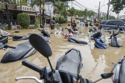 Los rescatistas caminan a través de las aguas de la inundación cerca de motocicletas sumergidas en una zona residencial de Bekasi, Java Occidental, Indonesia, el 4 de marzo de 2025.