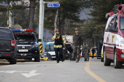 El personal de los servicios de rescate y los soldados caminan cerca del lugar del bombardeo accidental de un avión de combate, en Pocheon, el 6 de marzo de 2025.